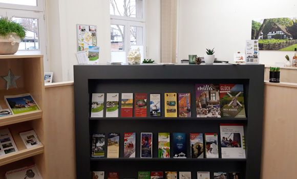 Innenraum der Tourist‑Info Rahden mit Prospektregal und Infomaterial.