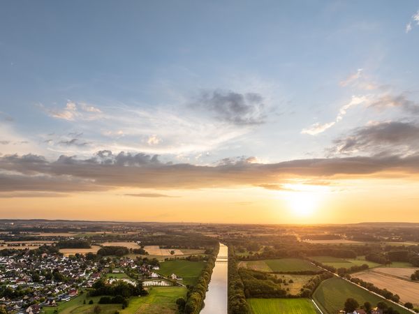 Luftaufnahme zeigt Mittellandkanal bei Schloss Benkhausen, umgeben von grünen Feldern und Waldflächen.