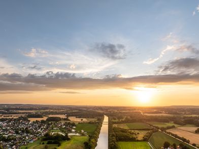 Luftaufnahme zeigt Mittellandkanal bei Schloss Benkhausen, umgeben von grünen Feldern und Waldflächen.