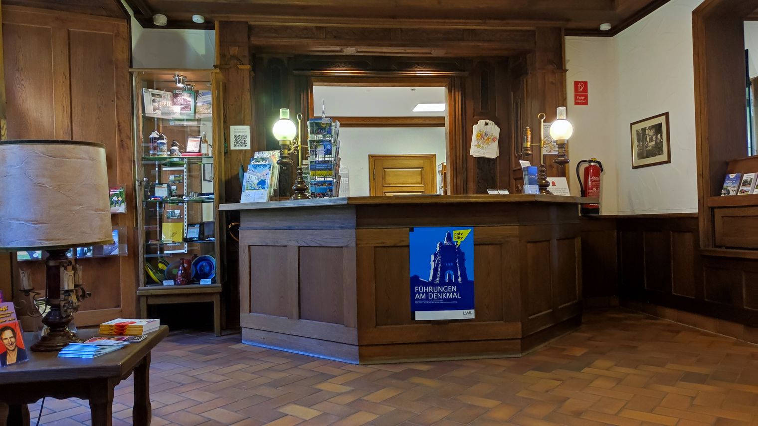 Holzvertäfelter Raum mit großem Holz-Tresen bestückt mit Informationsmaterial für eine Touristinofrmation