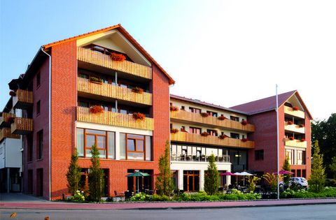 Rotes Backsteingebäude mit mehreren Stockwerken, Balkonen und großen Fenstern in ruhiger Umgebung.